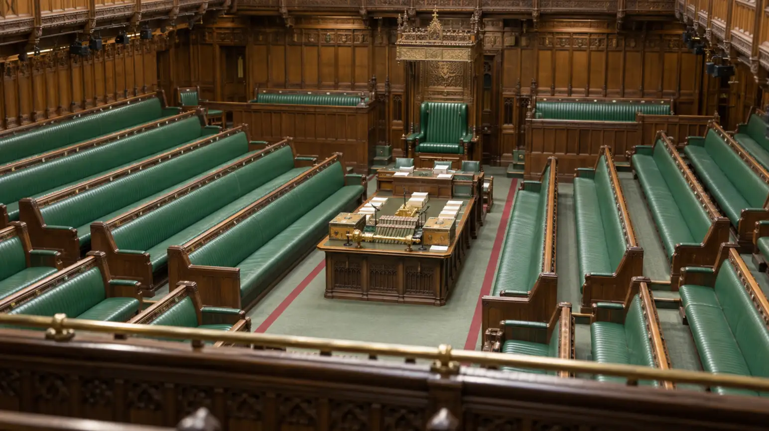 Empty green benches and the central table inside the UK House of Commons.