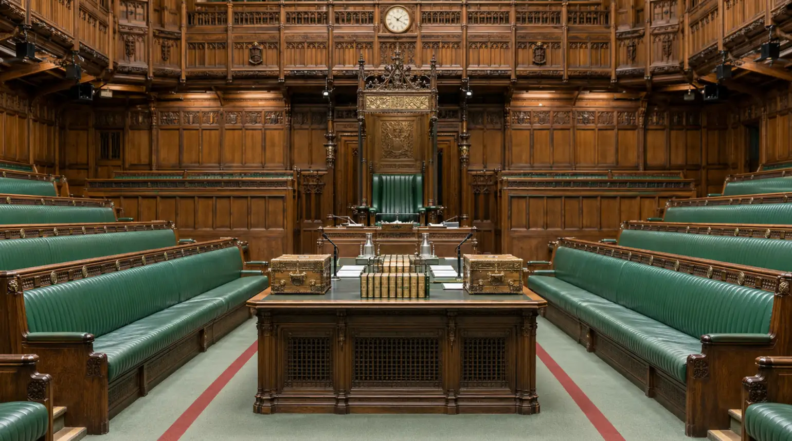 The empty House of Commons chamber with green benches and its central table.